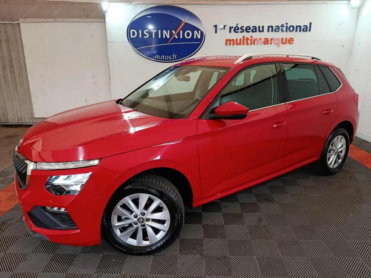 Vue 3/4 avant gauche d'un Skoda Kamiq rouge 2024 avec jantes alliage et barres de toit argentées.