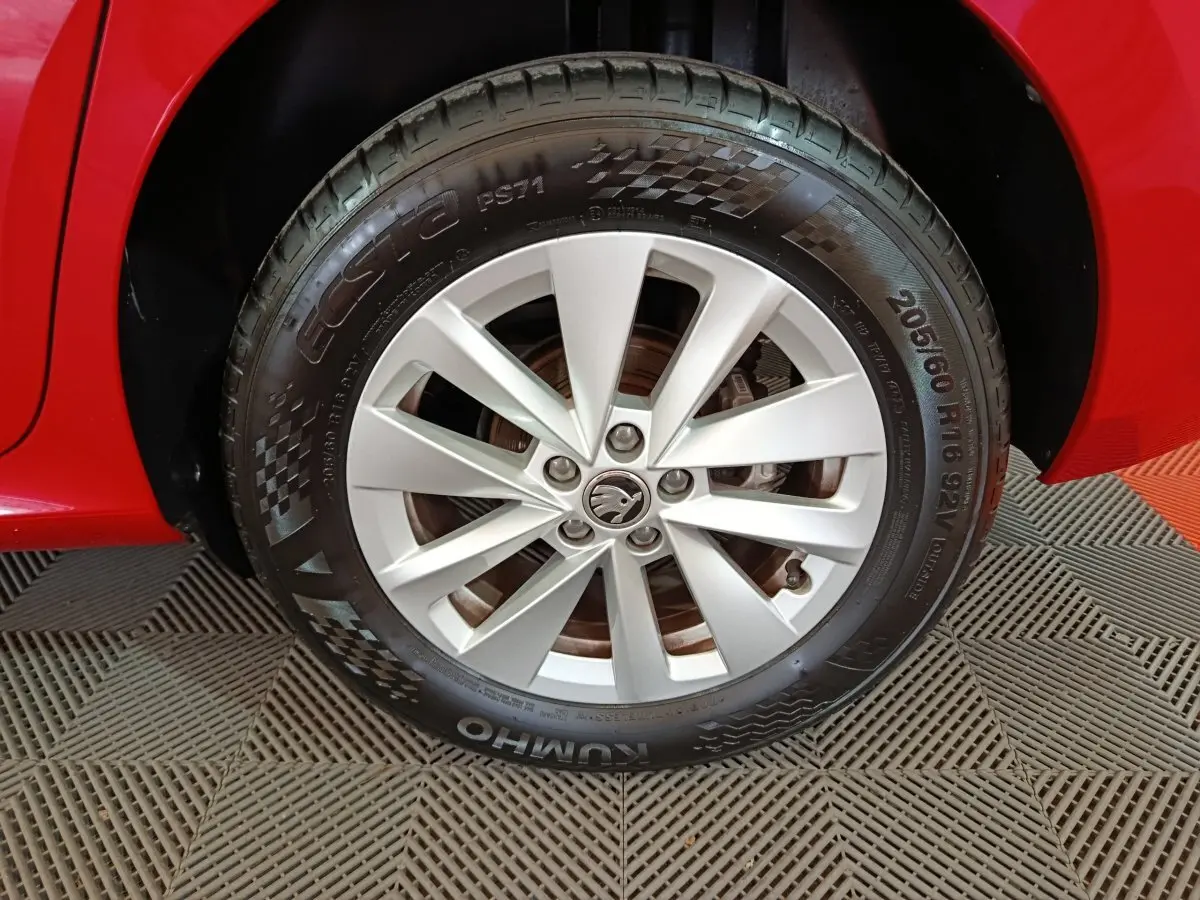 Gros plan sur la roue avant droite argentée d’un Skoda Kamiq rouge, avec jante à 5 doubles branches.
