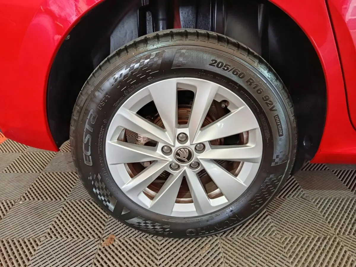 Gros plan sur la roue avant gauche d’un SKODA KAMIQ rouge, mettant en valeur la jante argentée et le pneu Ecsta.
