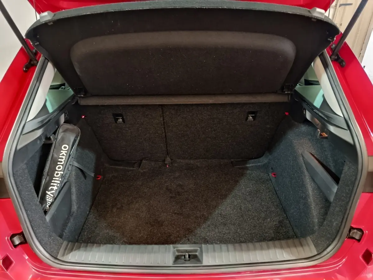 Coffre ouvert vu de l'arrière d'un Skoda Kamiq rouge 2024, espace de chargement propre et bien aménagé.