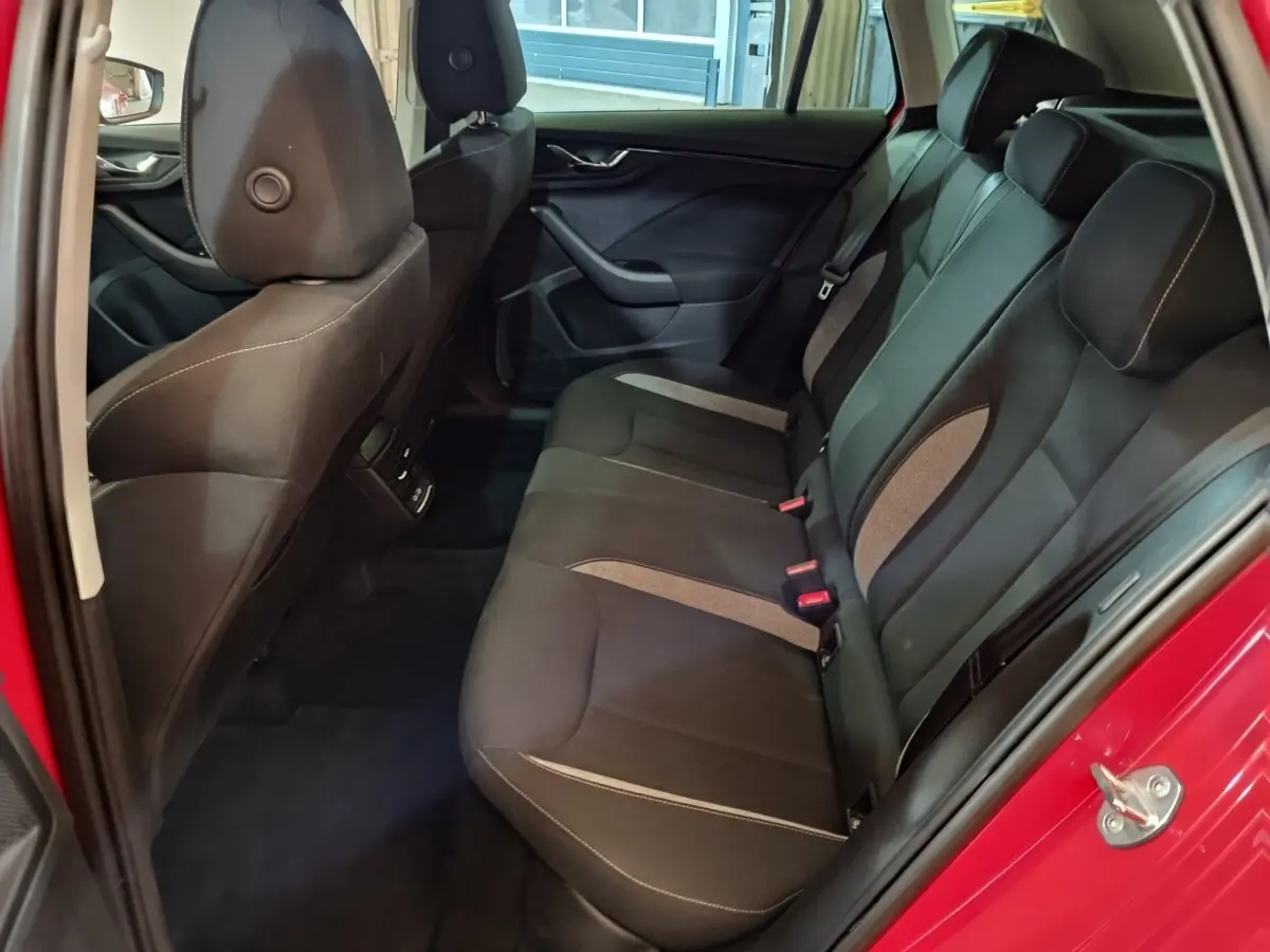 Vue intérieure côté droit sur la banquette arrière noire du Skoda Kamiq rouge 2024 avec portes ouvertes.