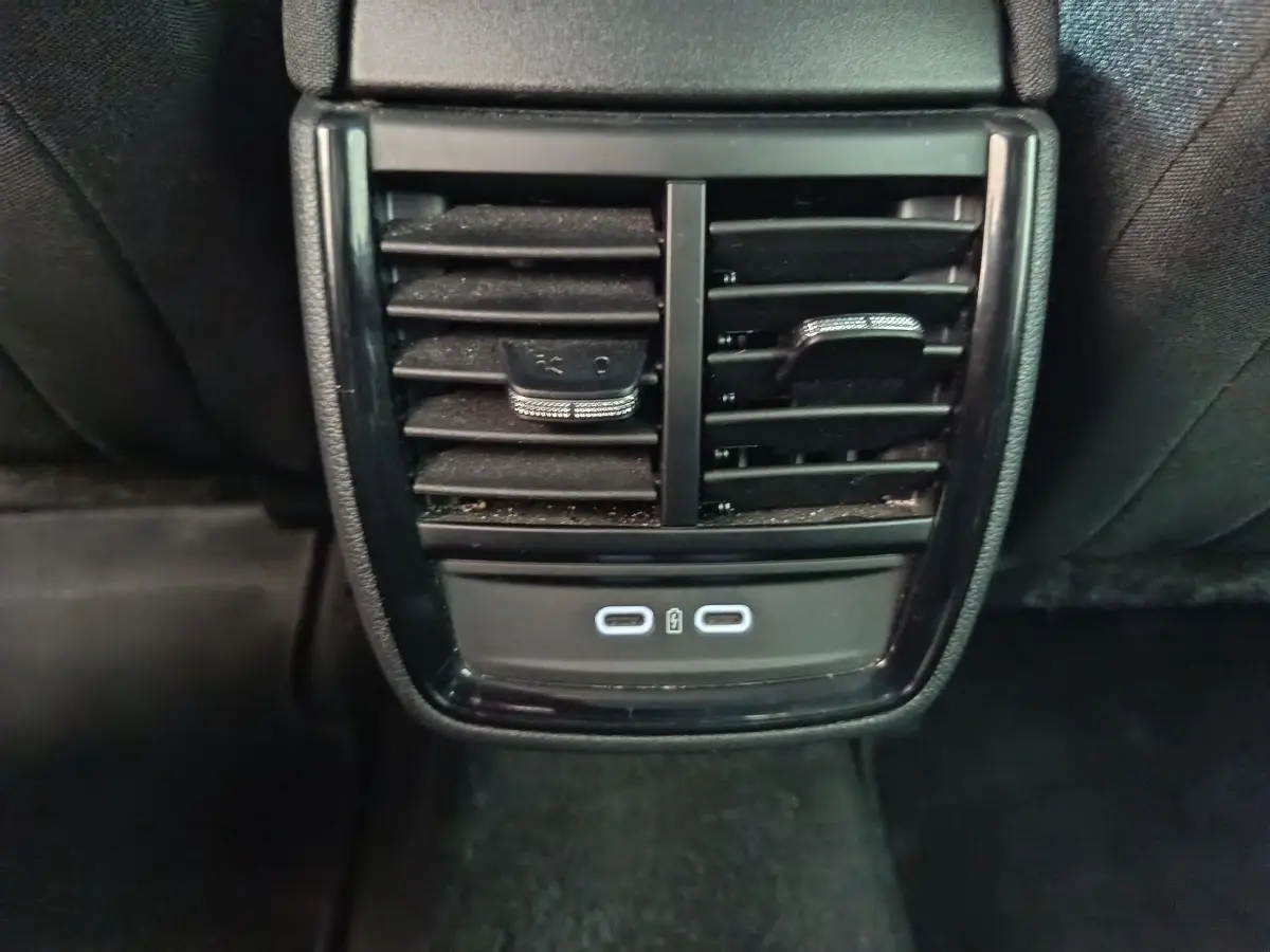 Vue rapprochée des aérateurs arrière noirs et des deux ports USB-C illuminés du Skoda Kamiq rouge 2024.