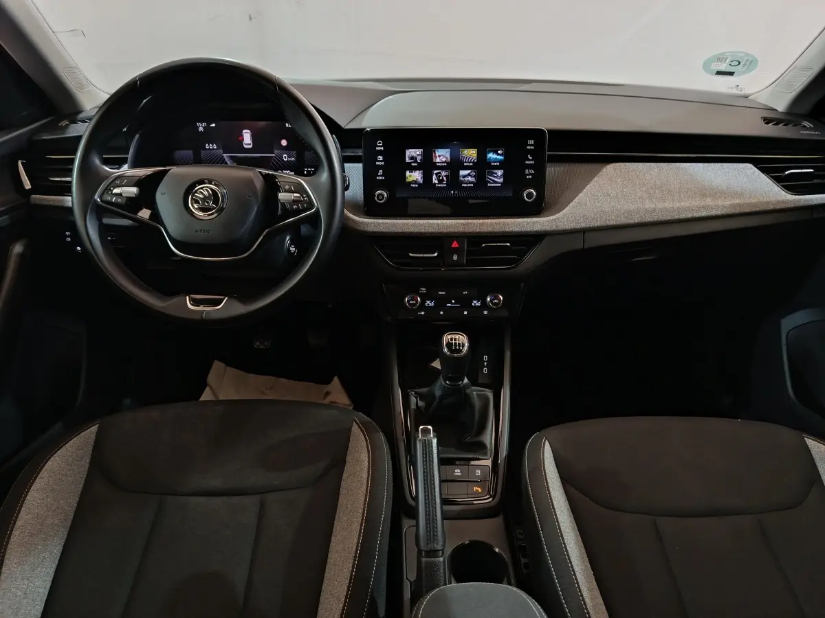 Vue intérieure frontale du tableau de bord et volant cuir multifonctions du Skoda Kamiq 2024 avec écran tactile central.