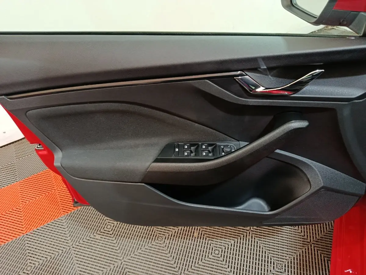 Vue rapprochée de la porte avant gauche noire avec commandes électriques sur une Skoda Kamiq rouge 2024.