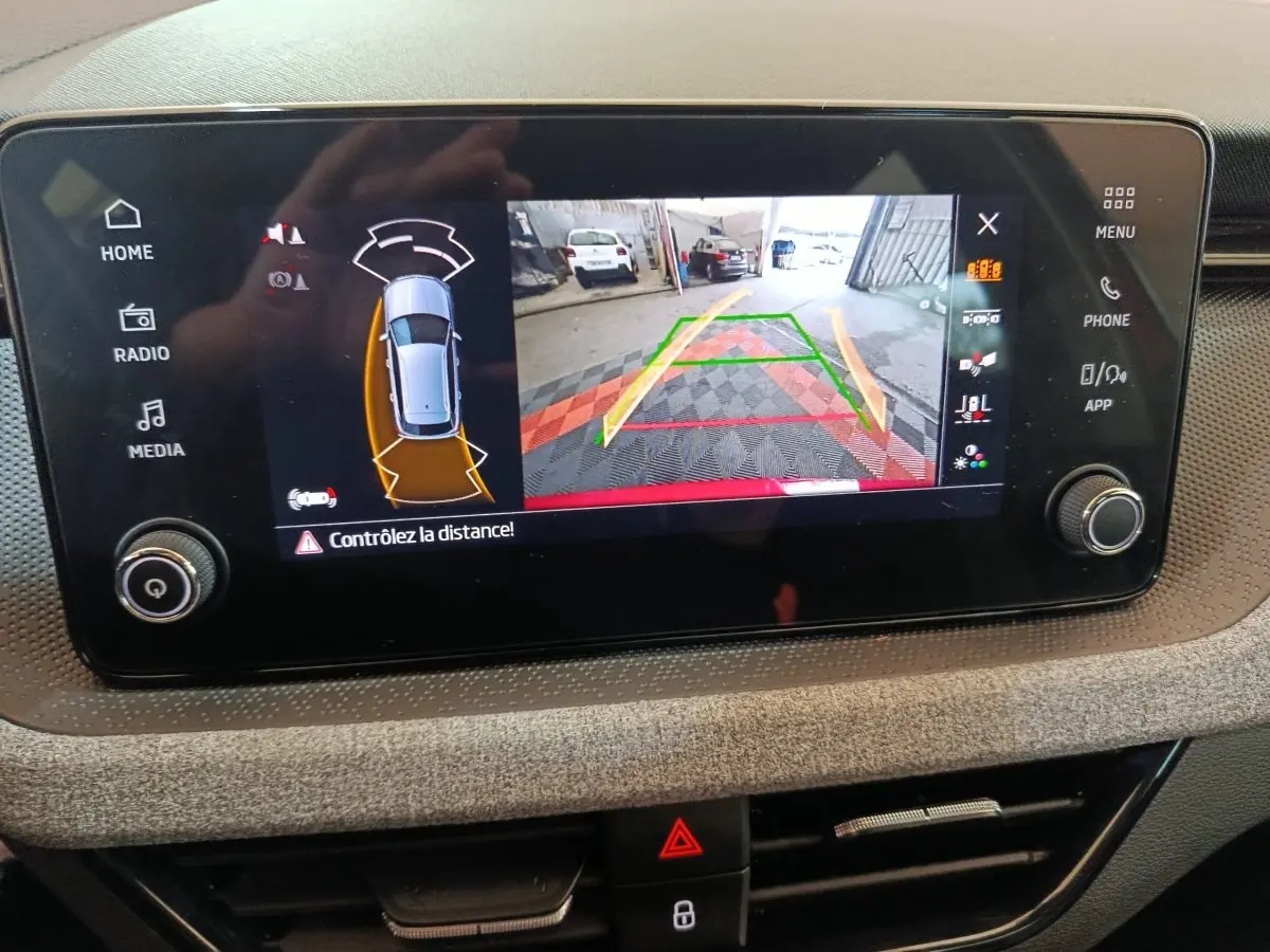 Écran tactile central du Skoda Kamiq 2024 montrant la caméra de recul avec alertes de distance et vue 360° du véhicule.
