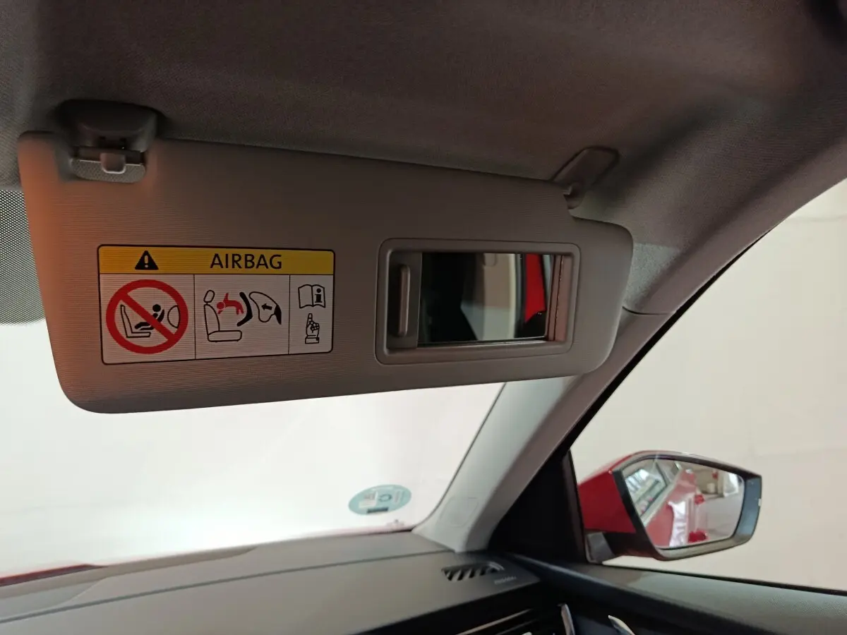 Intérieur côté conducteur du Skoda Kamiq rouge 2024, avec pare-soleil ouvert et rétroviseur latéral visible.