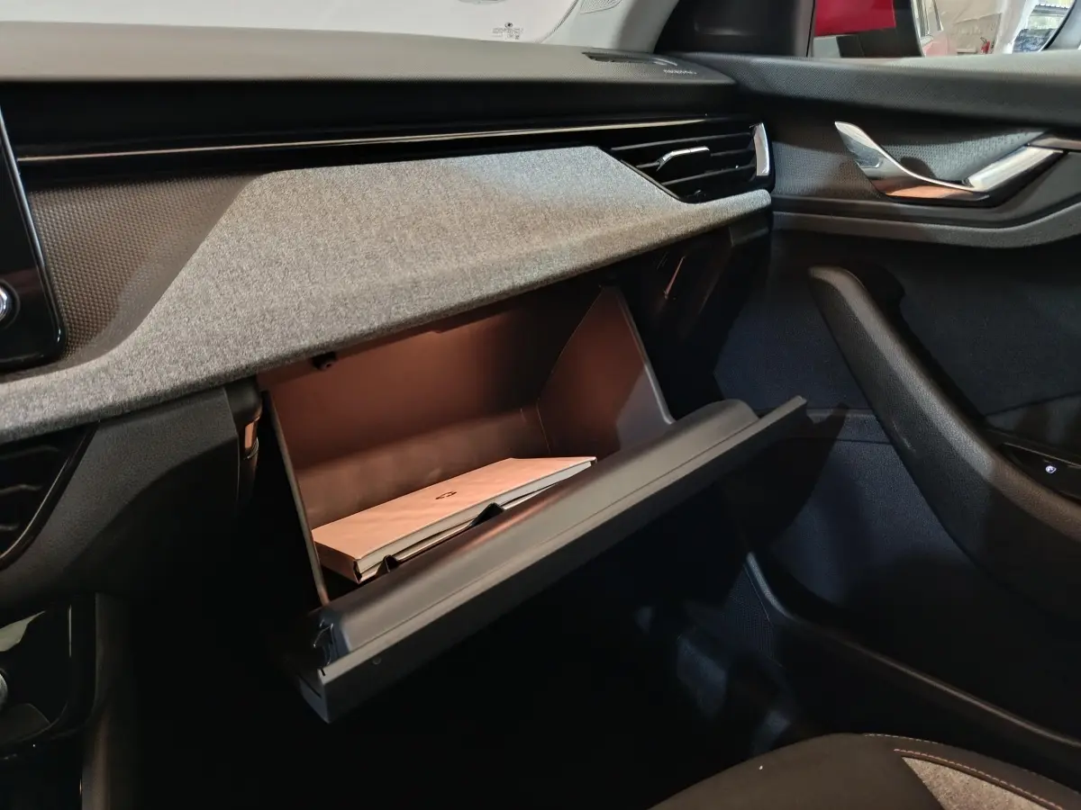 Intérieur SKODA KAMIQ 2024, vue sur la boîte à gants ouverte côté passager avec tableau de bord gris et noir.