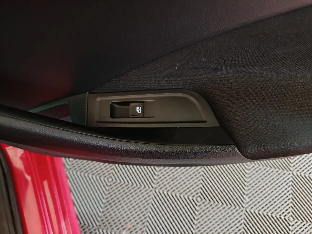 Gros plan sur le bouton de verrouillage des portes côté conducteur d’un Skoda Kamiq rouge 2024.