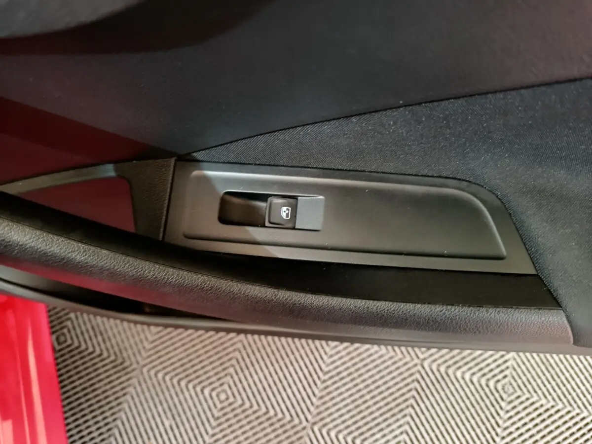 Détail de la commande de lève-vitre côté conducteur sur porte intérieure d’un Skoda Kamiq rouge.