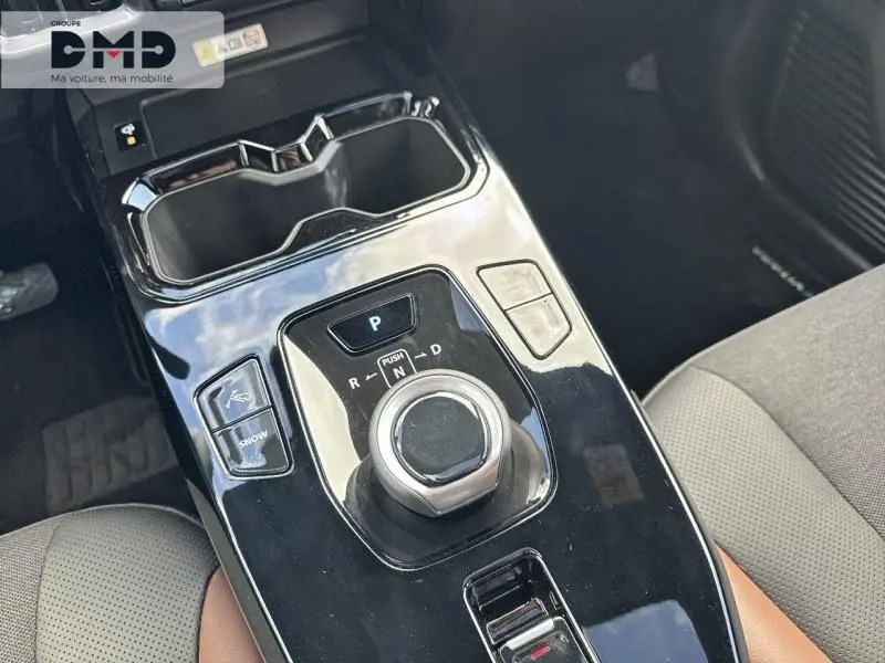 Gros plan sur la console centrale noire brillante du Suzuki Vitara 2026, avec sélecteur rotatif de boîte auto et sièges bi-ton.