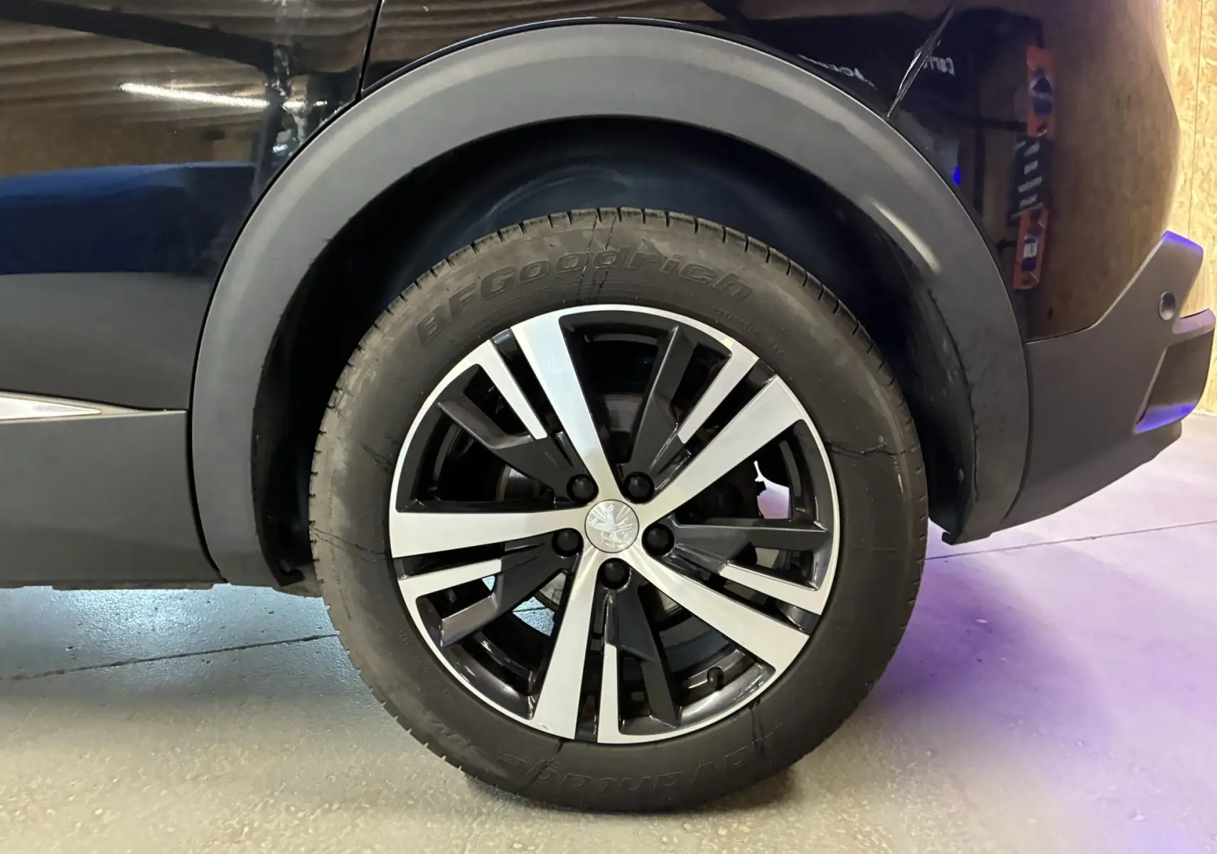 Gros plan sur la roue arrière droite d’un Peugeot 3008 noir, mettant en valeur la jante alliage bicolore et le pneu BFGoodrich.