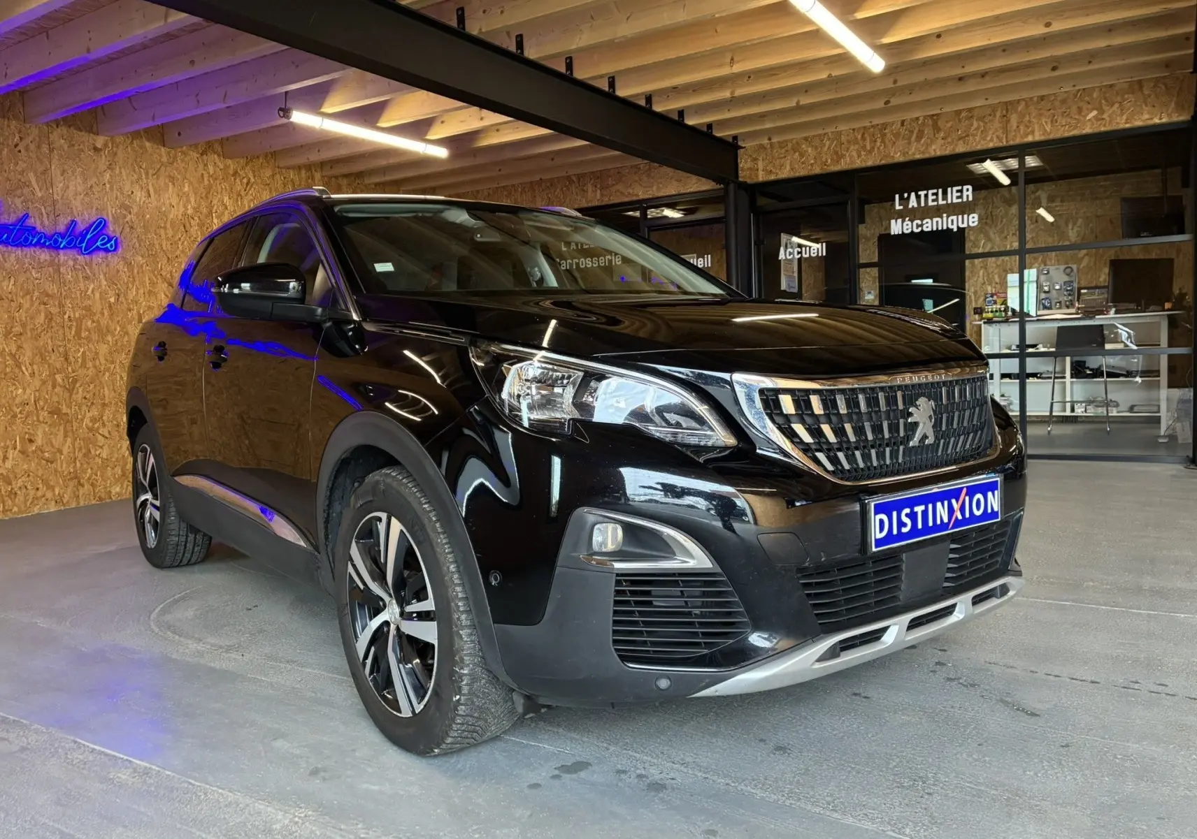 Peugeot 3008 noir vue 3/4 avant droit dans un garage avec calandre distinctive et jantes alliage.