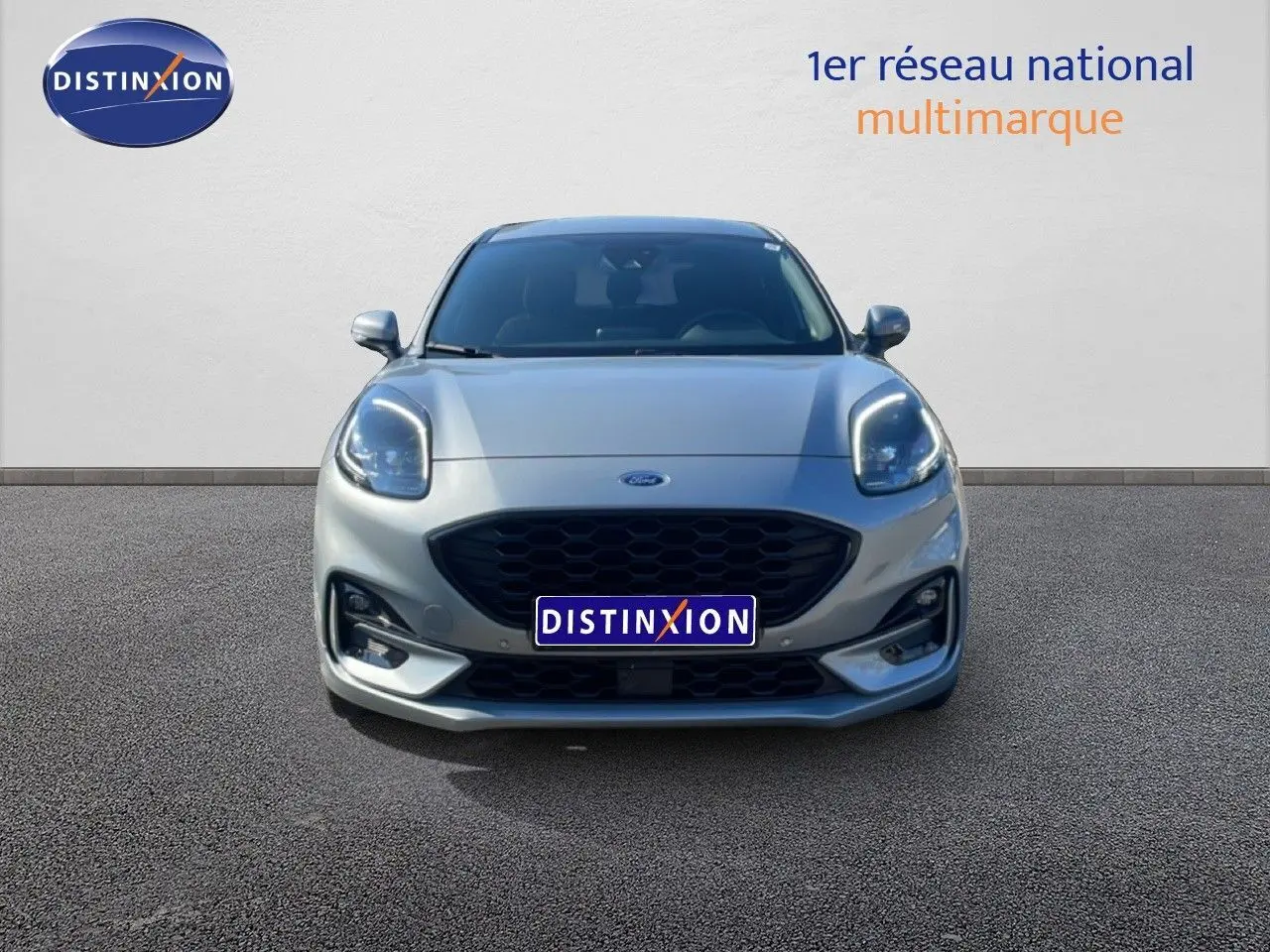 Vue frontale d'une Ford Puma gris Solar Metal 2023 avec calandre noire et phares LED allumés.