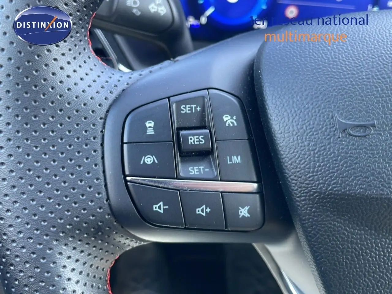 Gros plan sur les commandes de régulateur et volume au volant perforé noir du Ford Puma gris Solar Metal 2023.