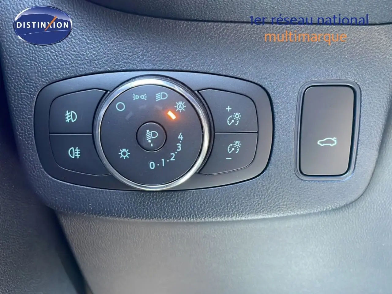 Gros plan sur les commandes d’éclairage et ouverture du coffre dans l’habitacle noir d’une Ford Puma 2023 gris Solar Metal.