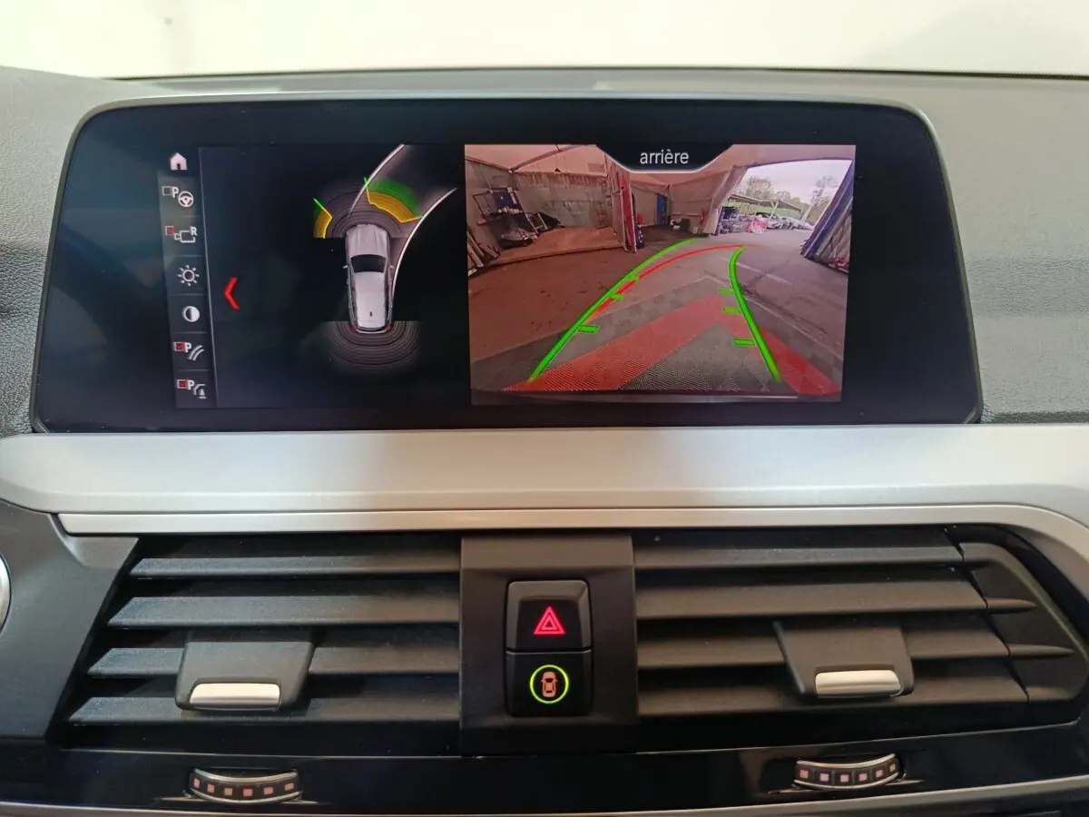 Écran central du BMW X3 xDrive30e 2020 montrant la caméra de recul et l’aide au stationnement en intérieur.