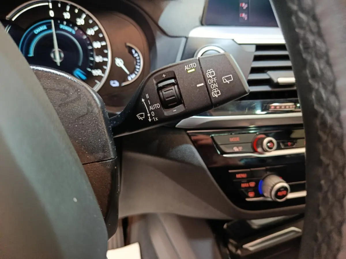 Gros plan sur la commande d’essuie-glace côté gauche du tableau de bord d’une BMW X3 gris foncé, intérieur moderne.