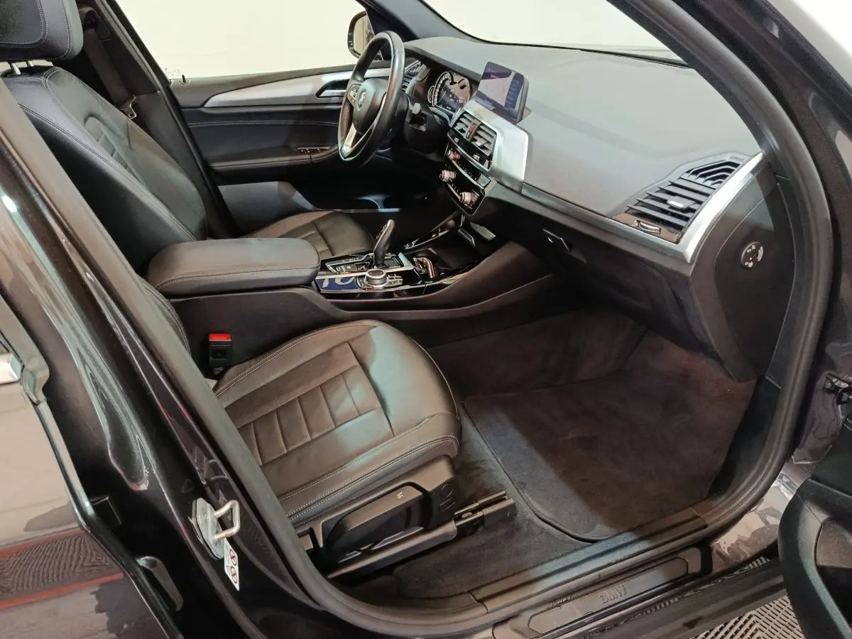 Intérieur avant droit BMW X3 xDrive30e 2020, sièges cuir noirs, tableau de bord moderne avec écran central et volant multifonctions.