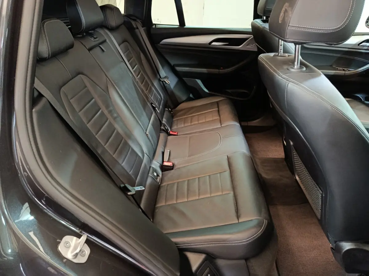 Vue intérieure côté gauche des sièges arrière en cuir noir du BMW X3 xDrive30e gris foncé, avec détails de couture apparents.