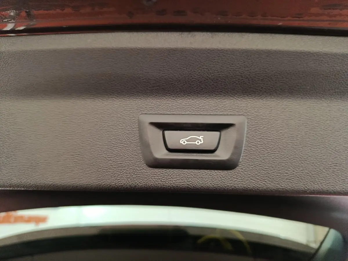 Bouton de fermeture électrique du coffre sur la partie intérieure du hayon d’un BMW X3 gris foncé.