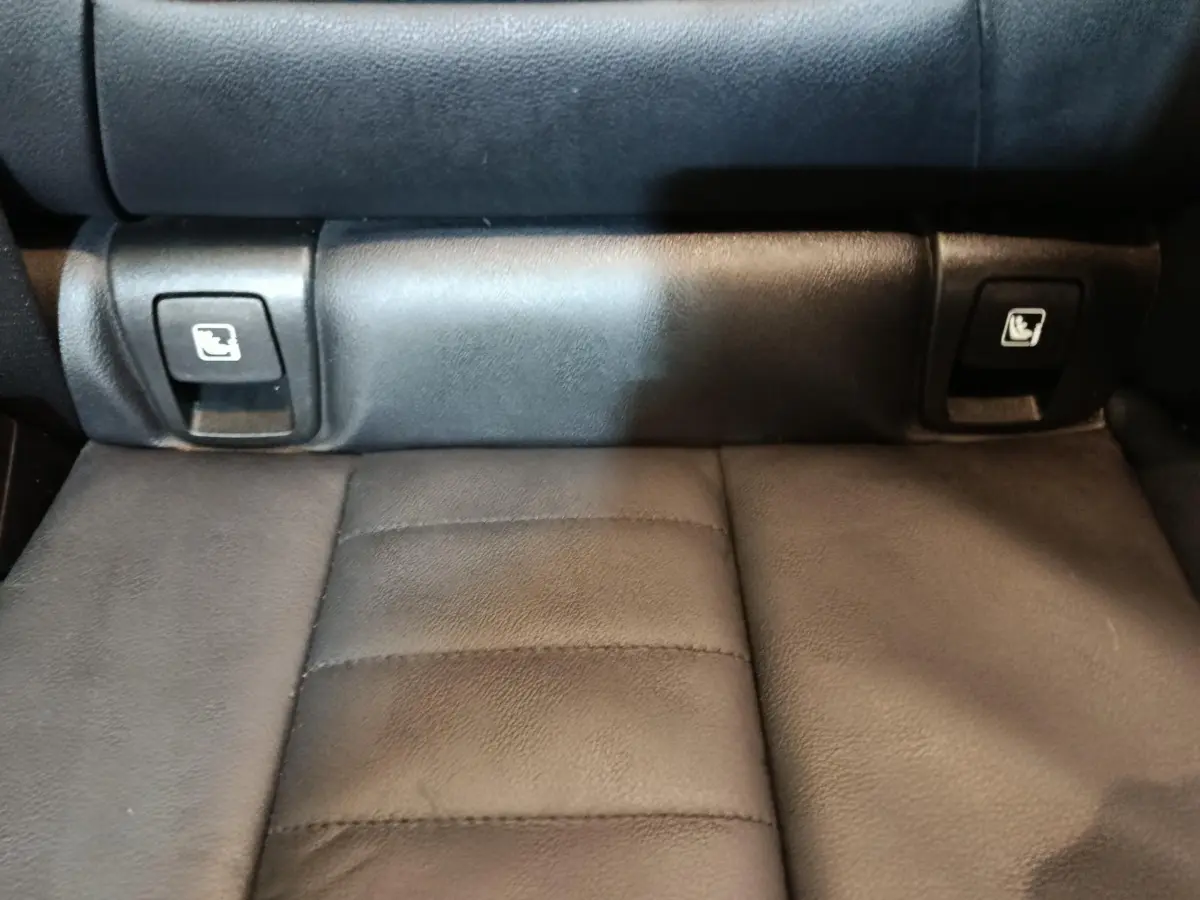 Gros plan sur les commandes de rabattement des sièges arrière en cuir noir du BMW X3 xDrive30e gris foncé.