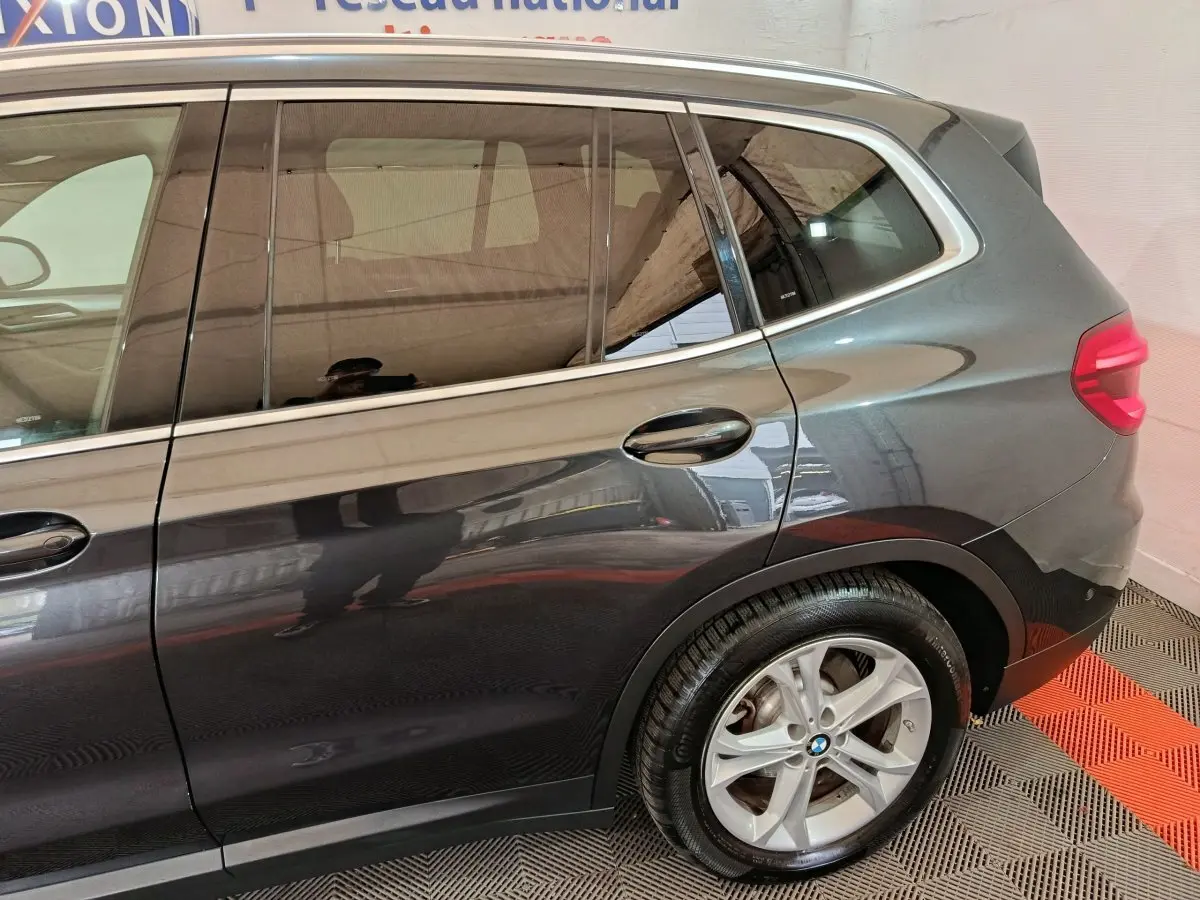 Vue côté droit arrière d’un BMW X3 xDrive30e gris foncé avec jante alliage et feux arrière LED visibles.
