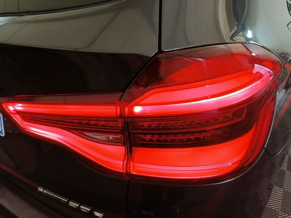 Gros plan sur le feu arrière droit allumé d’un BMW X3 xDrive30e gris foncé, soulignant son design lumineux distinctif.