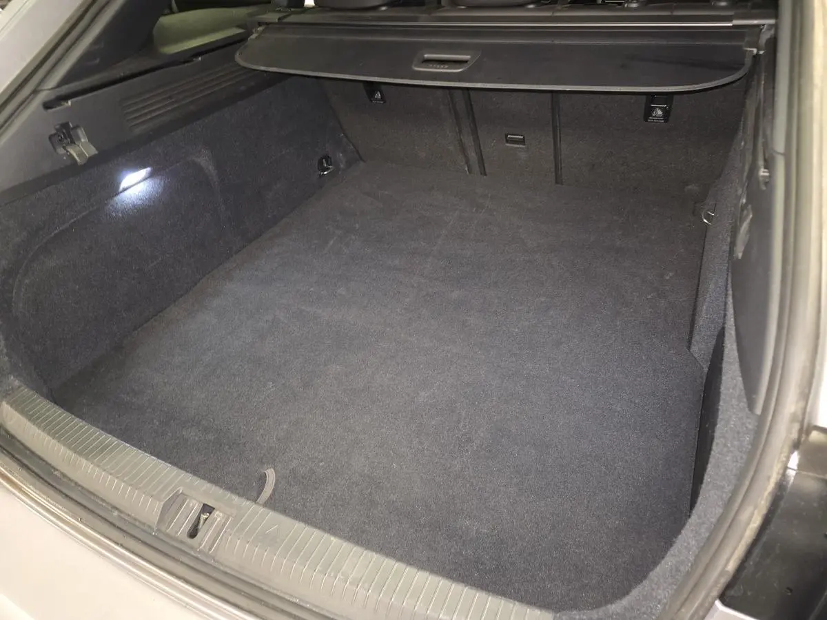 Coffre spacieux et propre du Volkswagen Arteon Shooting Brake gris, vu de l'arrière avec éclairage intérieur allumé.