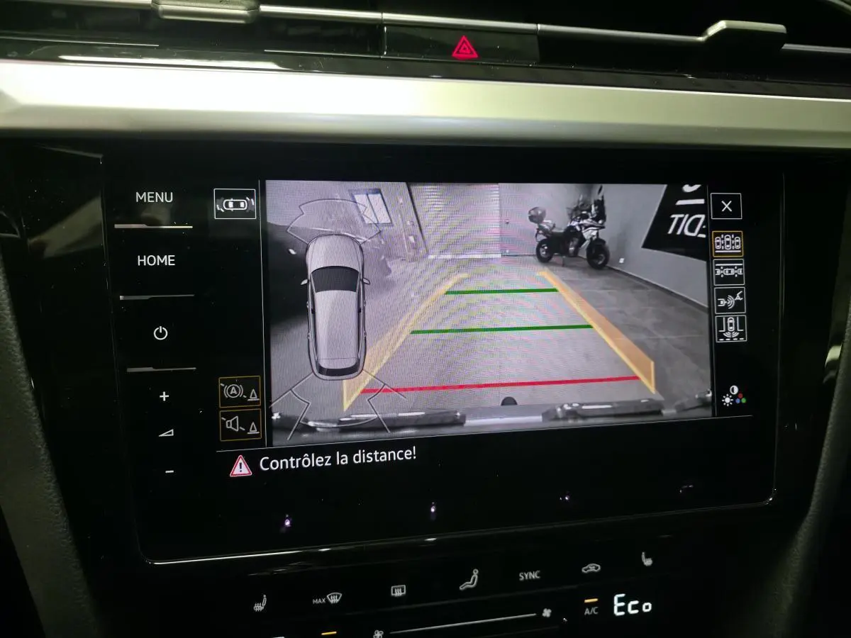 Écran intérieur affichant la caméra de recul et l'aide au stationnement du Volkswagen Arteon gris, vue de face.