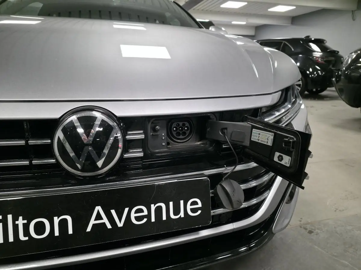 Vue rapprochée avant d’un Volkswagen Arteon gris avec prise de recharge hybride ouverte sur la calandre.