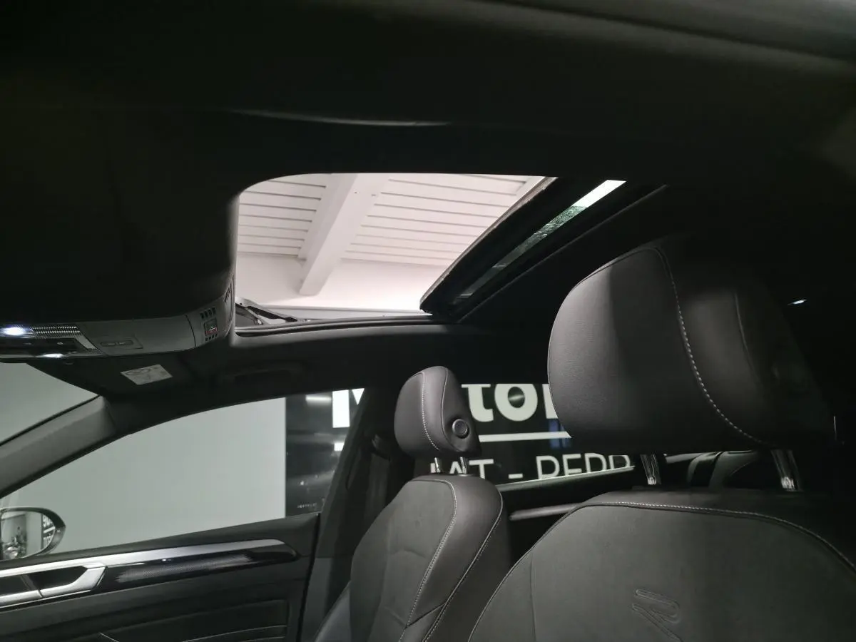 Vue intérieure du toit ouvrant coulissant en verre et des sièges avant noirs avec surpiqûres blanches du Volkswagen Arteon Shooting Brake R-Line.