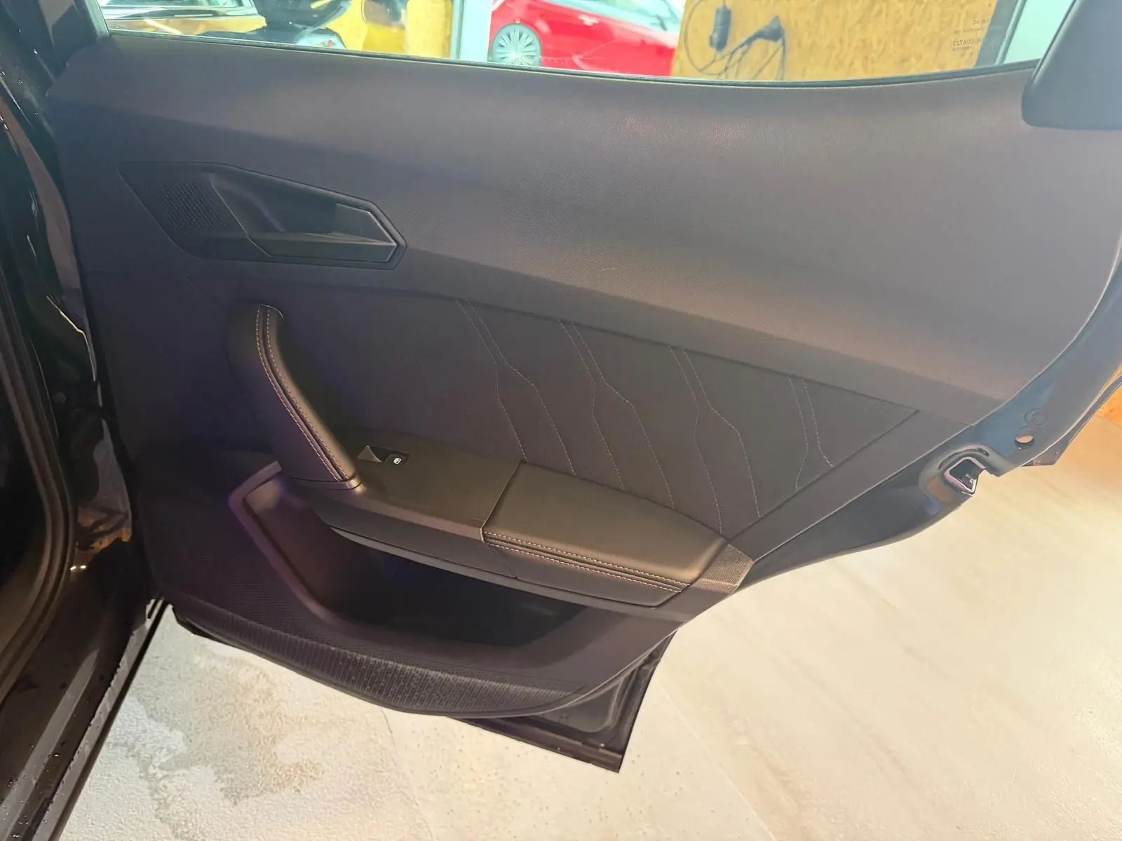 Vue intérieure de la porte arrière gauche noire du CUPRA Formentor 2025 avec garniture tissu et surpiqûres contrastées.