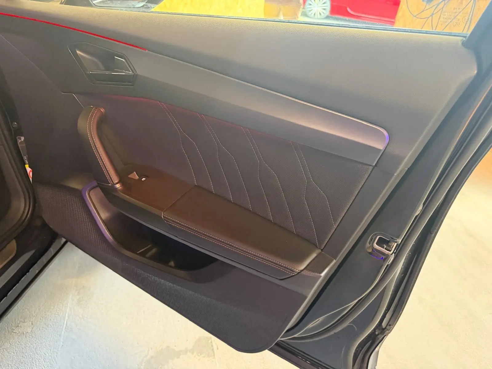 Vue rapprochée de la porte avant gauche noire du CUPRA Formentor 2025 avec surpiqûres orange et poignée intégrée.