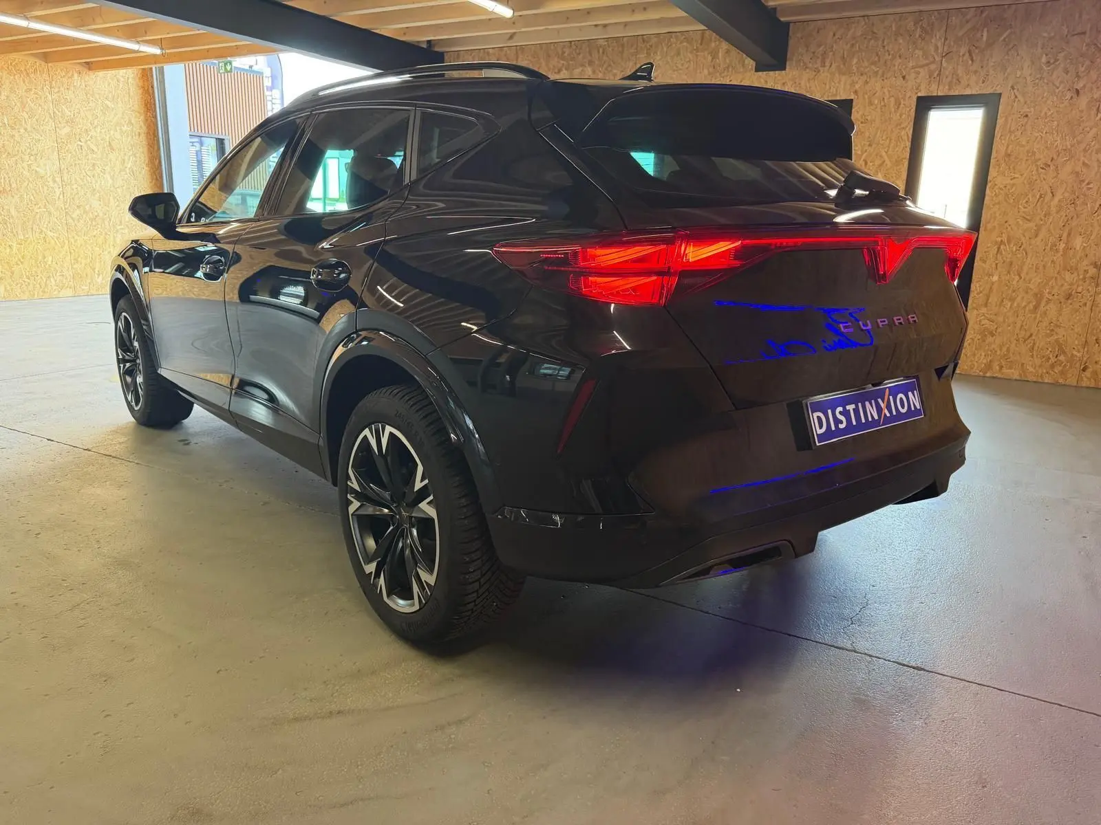 Vue 3/4 arrière droite du CUPRA Formentor noir 2025 avec jantes alliage et feux arrière LED allumés.