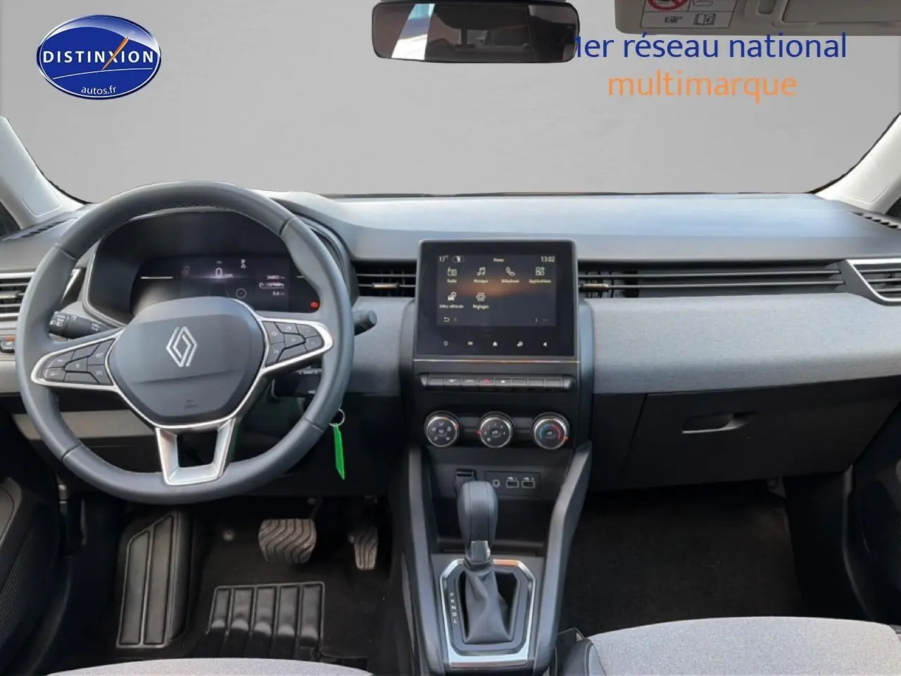 Vue intérieure avant de la Renault Clio V gris métal, avec tableau de bord moderne et écran tactile central.