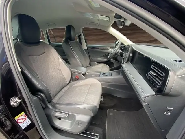 Vue intérieure côté gauche du Volkswagen Tiguan noir 2024, montrant les sièges avant et le tableau de bord moderne.