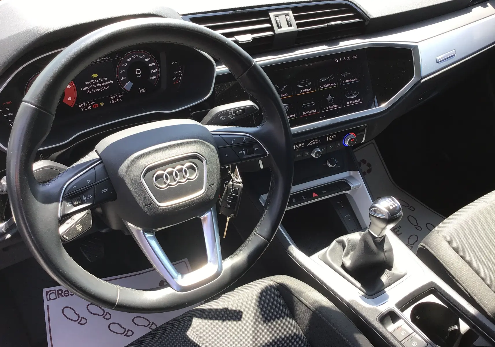 Vue intérieure de l'Audi Q3 Sportback 2024, tableau de bord noir avec volant cuir et levier de vitesse manuel.