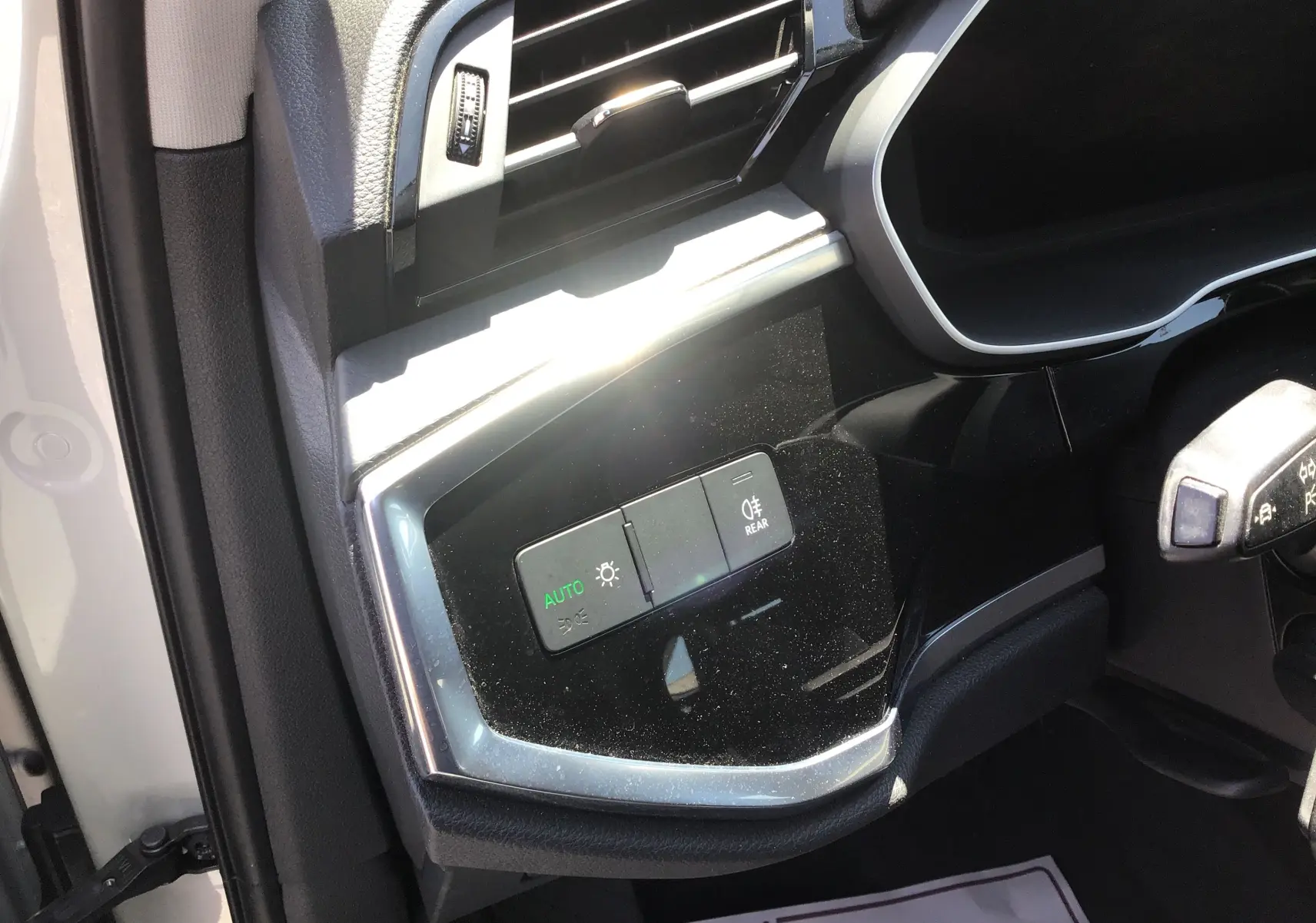 Gros plan sur les commandes d’éclairage côté gauche du tableau de bord d’un Audi Q3 Sportback gris clair 2024.