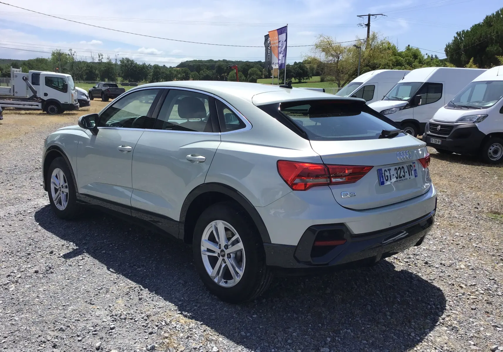 Audi Q3 Sportback gris clair métal vue 3/4 arrière droit, soulignant ses lignes fluides et ses feux arrière distinctifs.