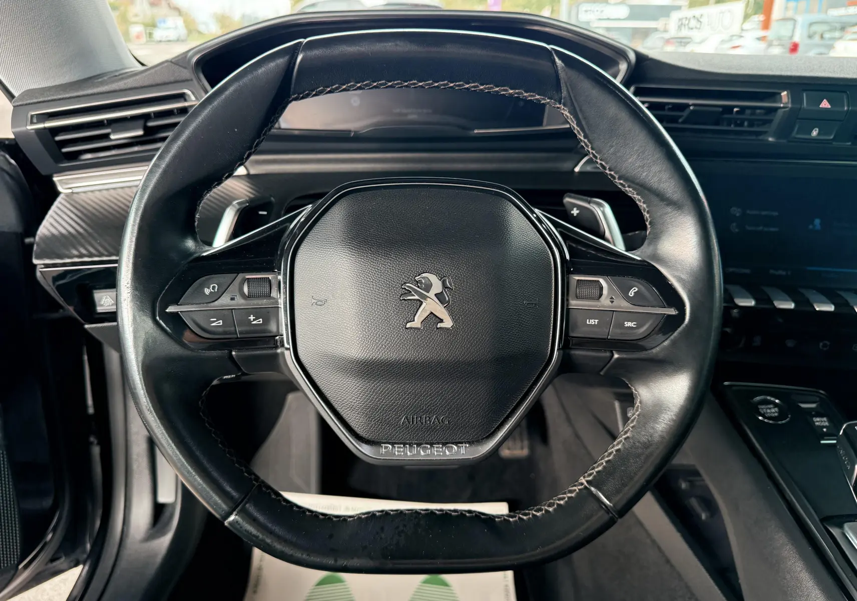 Vue rapprochée du volant noir en cuir de la Peugeot 308 SW 2018 avec commandes intégrées et logo lion central.