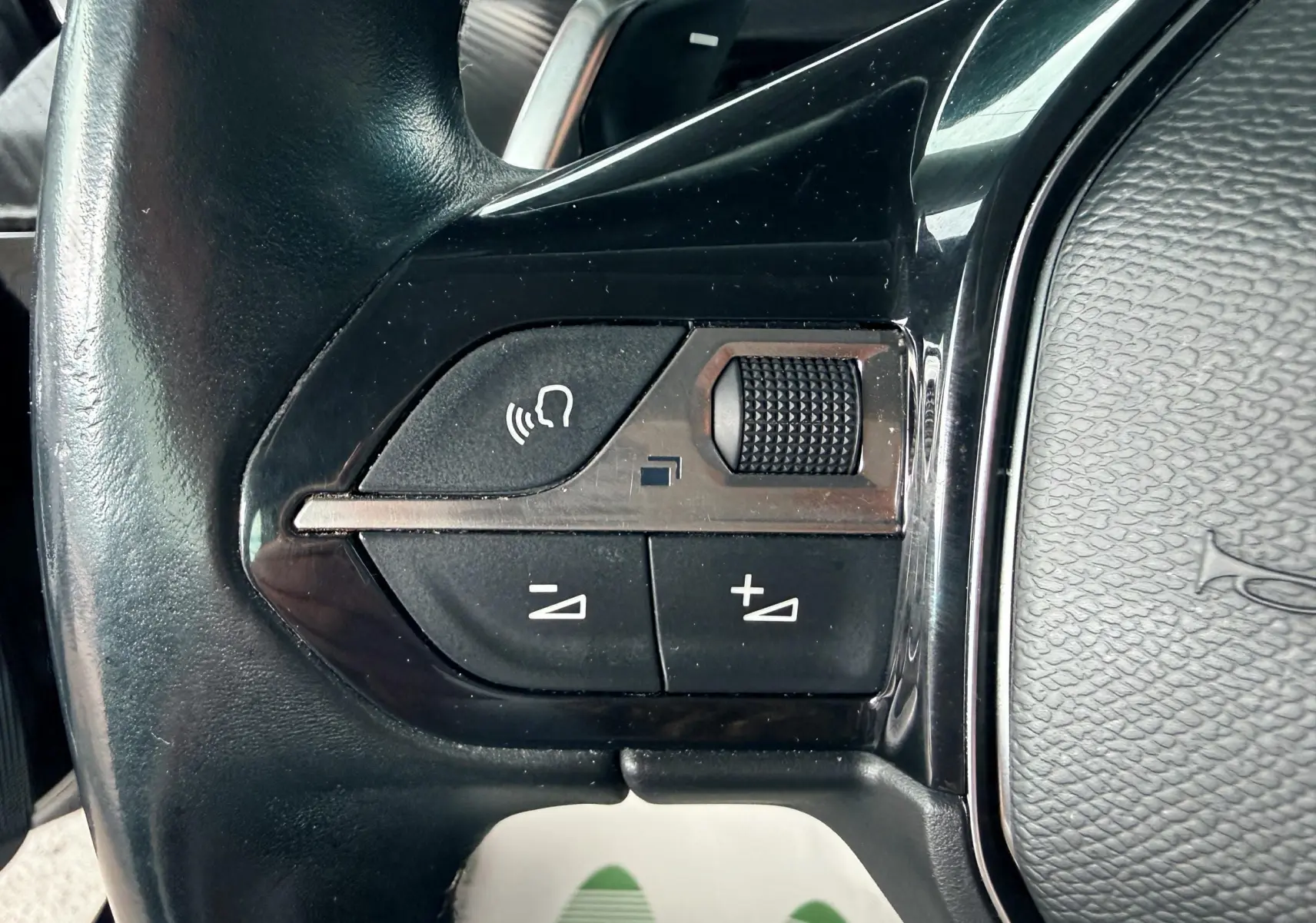 Gros plan sur les commandes vocales et volume sur le volant noir de la Peugeot 308 SW 2018.