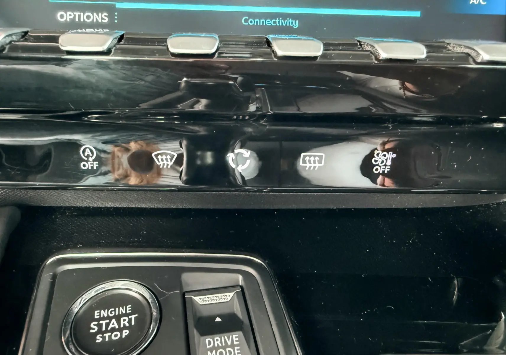 Gros plan sur la console centrale noire de la Peugeot 308 SW avec bouton start/stop et commandes de climatisation.