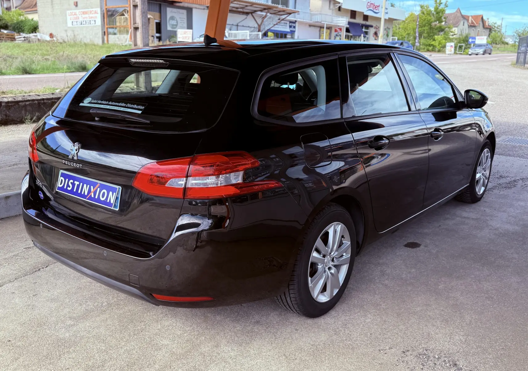 Peugeot 308 SW noir métal vue 3/4 arrière côté droit, avec feux arrière allongés et jantes alliage 16 pouces.