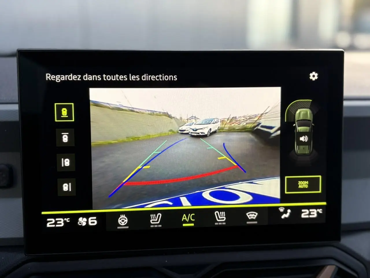 Écran tactile montrant la caméra de recul avec vue arrière du Dacia Bigster noir nacré en stationnement.