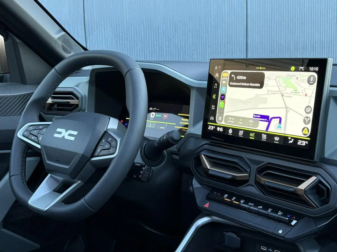 Vue intérieure du tableau de bord et volant noir du Dacia Bigster 2026 avec écran tactile de navigation et aérateurs hexagonaux.