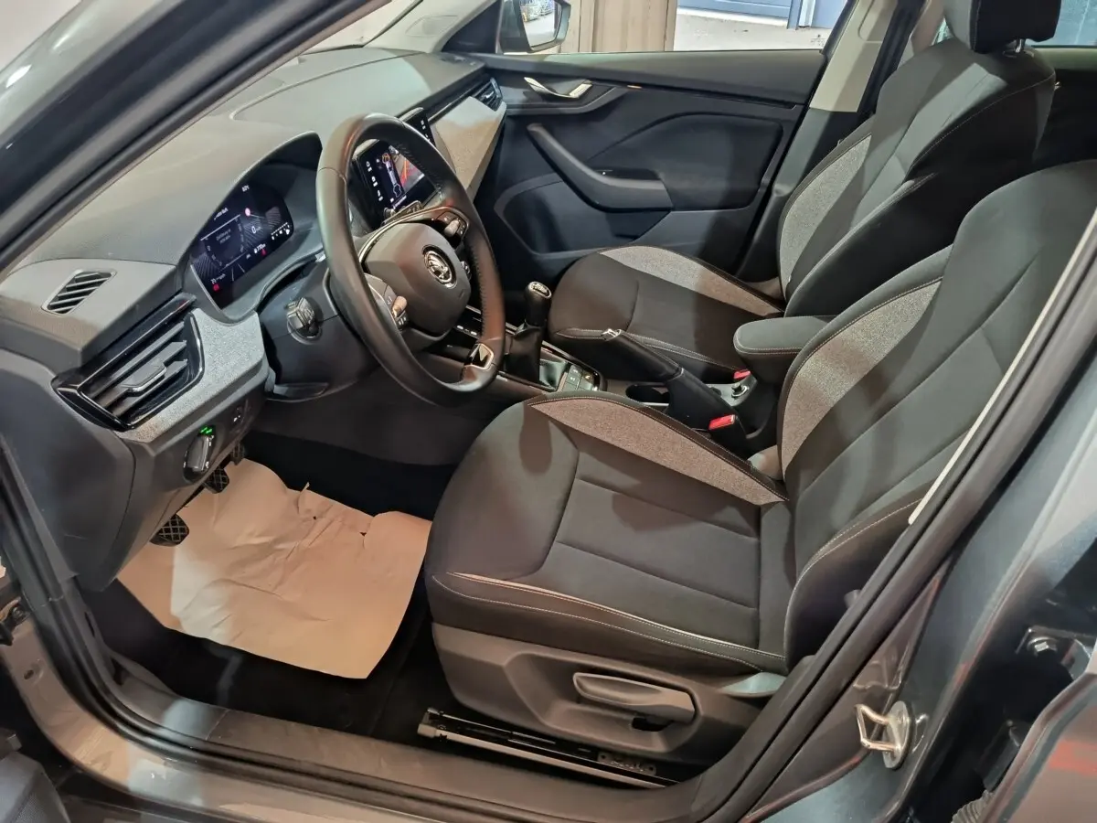 Vue intérieure côté conducteur du Skoda Kamiq 2024 gris clair, volant cuir multifonctions et tableau de bord numérique.
