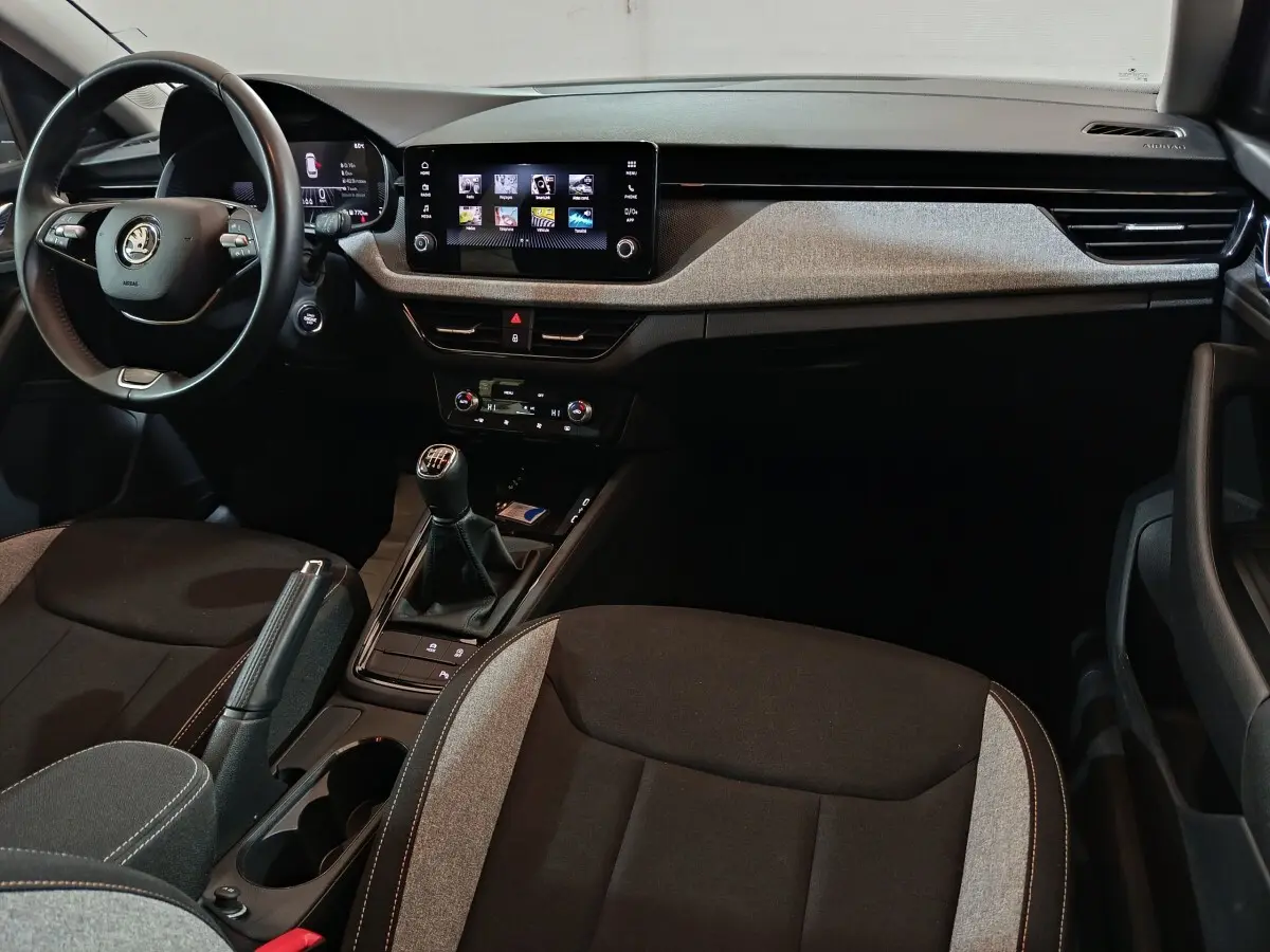 Vue intérieure avant du Skoda Kamiq 2024 avec volant cuir multifonctions, écran tactile central et boîte manuelle.