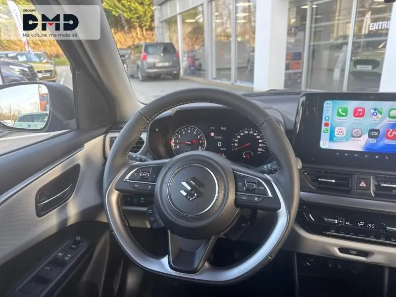 Vue intérieure centrée sur le volant cuir multifonction de la Suzuki Swift 1.2 Hybrid avec écran tactile et tableau de bord digital.