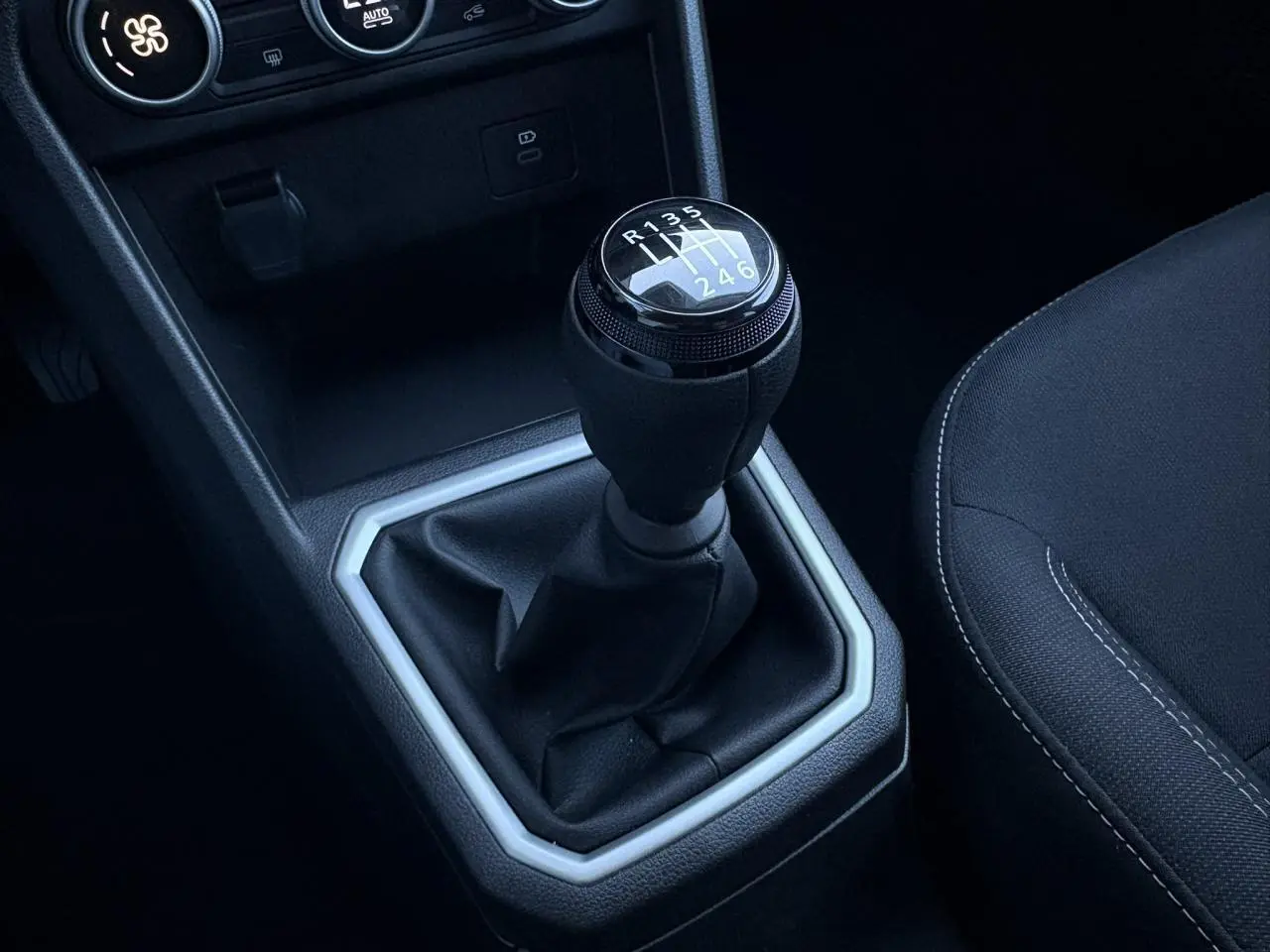 Le levier de vitesses manuel noir de la Dacia Jogger 2025 avec coutures blanches sur siège tissu gris.