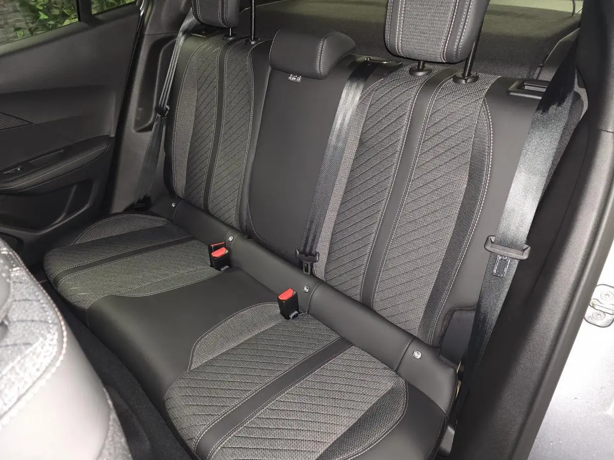 Vue intérieure côté droit sur la banquette arrière gris foncé avec surpiqûres et ceintures de sécurité du Peugeot 2008 hybride 2025.